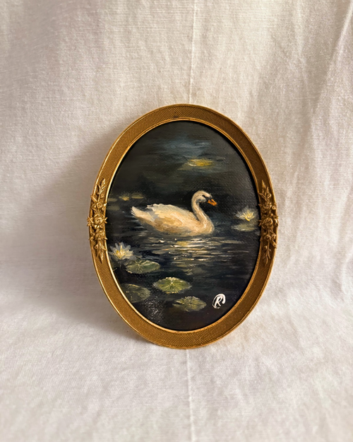 Original oil painting of a beautiful white swan in a small vintage antique brass Herman Lindell oval frame. Deep rich blue tones with reflective whimsical sparkles and lily pads. Moody cottagecore style painting.