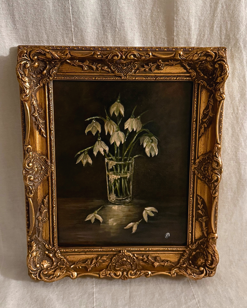 Decorative painting of snowdrops in a glass vase within an ornate gold frame, zoomed in photograph.
